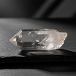 Clear Quartz point glowing on a dark background, Master Healer crystal – Horocosmo