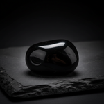 Natural Black Obsidian crystal with inner glow on dark background – Horocosmo