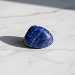 Natural Lapis Lazuli crystal with golden pyrite flecks on white marble – Horocosmo