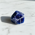 Natural Sodalite crystal blue with white veins on white marble – Horocosmo
