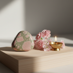 Unakite stone on a meditation altar with brass diya and pink flowers – Horocosmo
