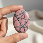 Natural Rhodonite stone held in hand for scale – Horocosmo