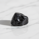 Natural black Shungite stone on white marble – Horocosmo