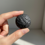 Natural black Shungite stone held in hand for scale – Horocosmo