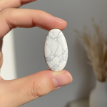 Natural white Howlite stone held in hand for scale – Horocosmo