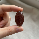 Man-made Goldstone held in hand for scale – Horocosmo