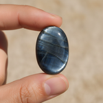 Natural Hawk's Eye stone held in hand for scale – Horocosmo