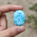 Natural Larimar ocean-blue stone held in hand for scale – Horocosmo