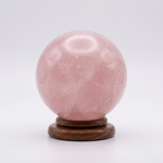 Natural Rose Quartz crystal sphere on wooden stand – representative image; each natural stone varies slightly in pattern and shade